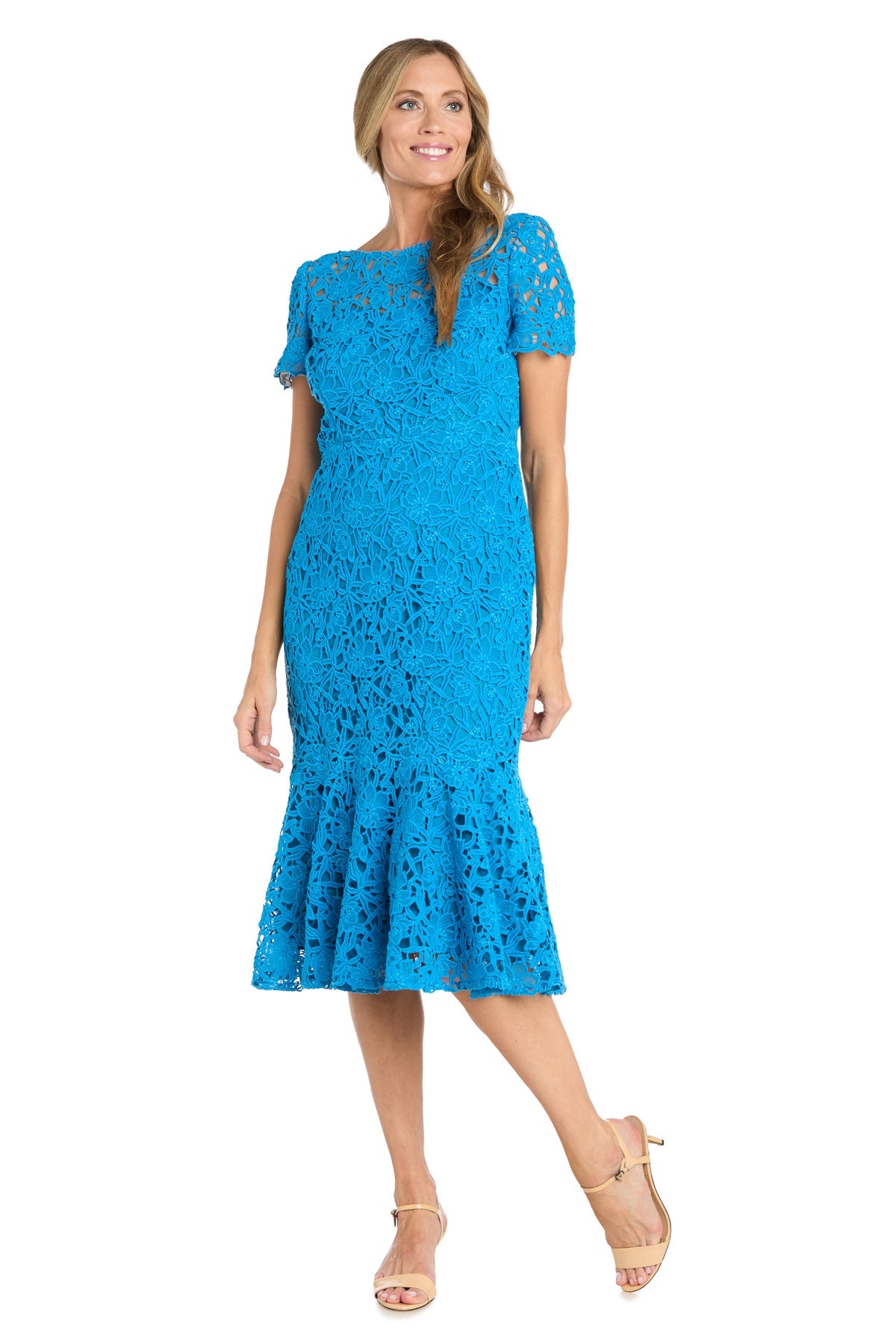 A woman wears the R&M Richards 3498 Midi Lace Wedding Guest Dress in bright blue with short sleeves and ruffled hem, paired with nude strappy heels.